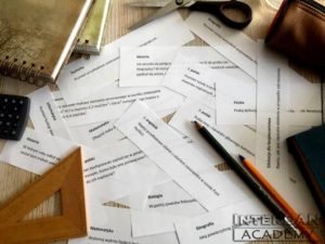 kartki z pytaniami na stole wśród przyrządów szkolnych